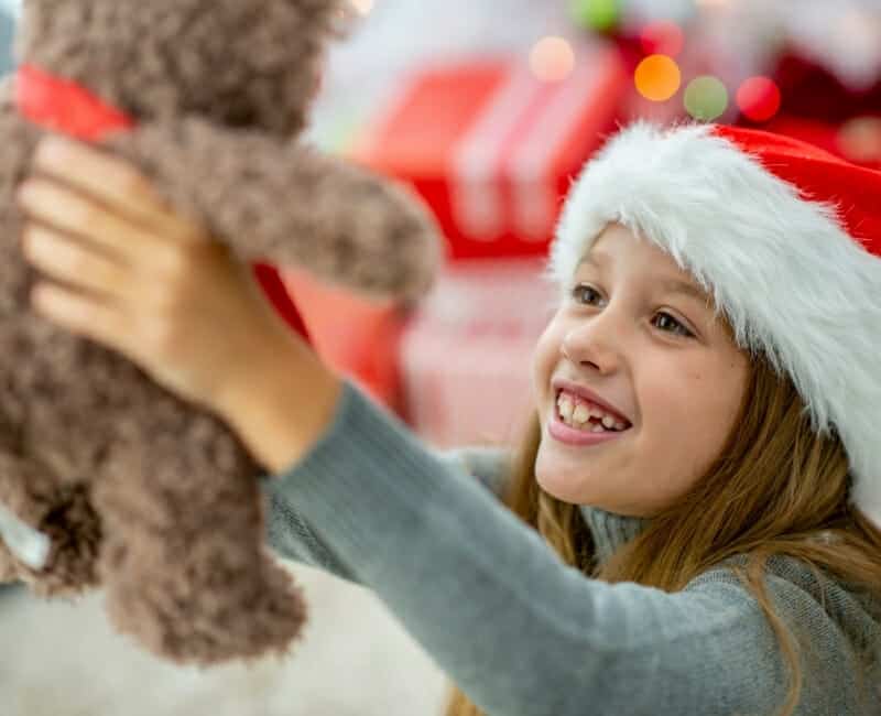 Minimalist Christmas: Child wearing a santa hat holding a teddy bear