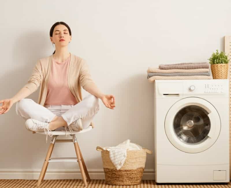 Overwhelmed by laundry: woman meditating in laundry room