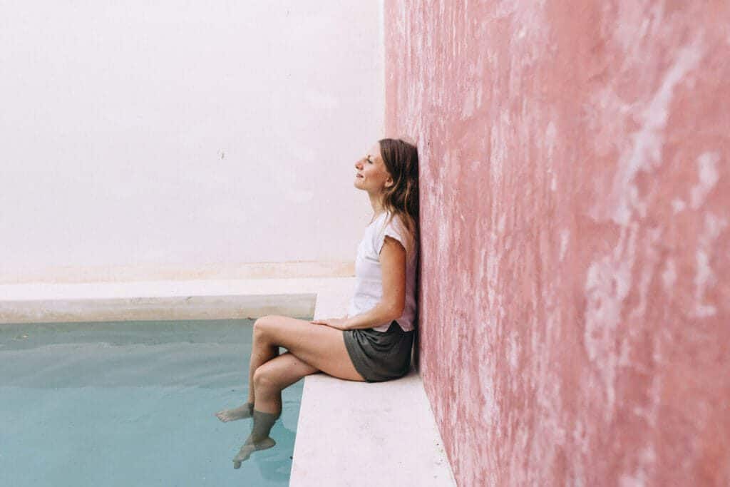 Woman sitting against a wall with feet in pool